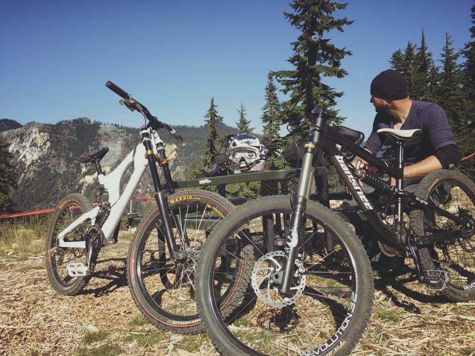 Two downhill bikes resting together at a mountaintop stop
